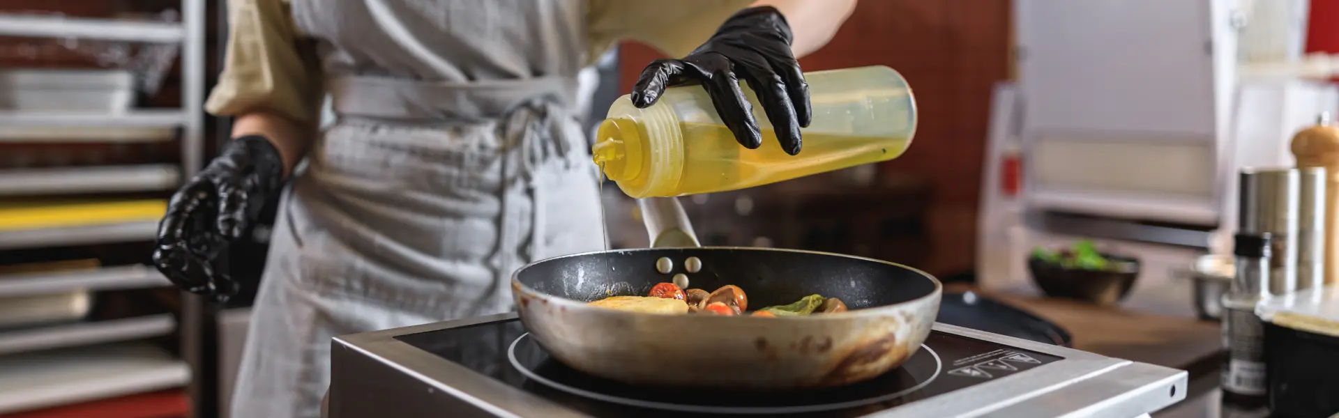 Professional chef uniform adds oil into pan with dish restaurant kitchen